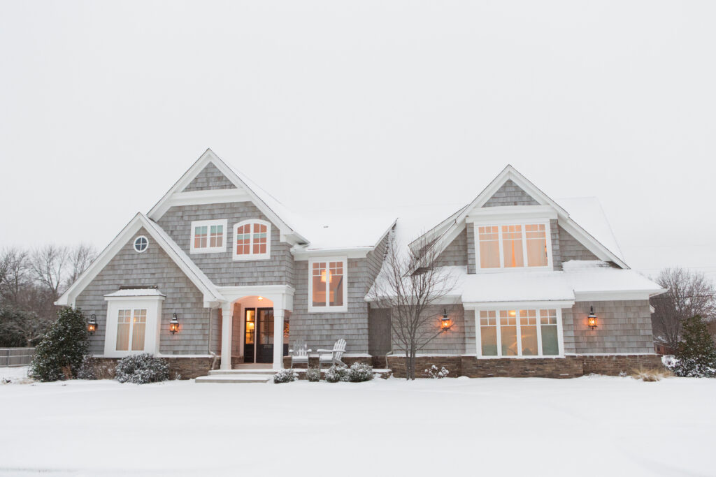 Wood-Shingled-Home-In-Snow-With-Warm-Lights-Illuminating-Windows